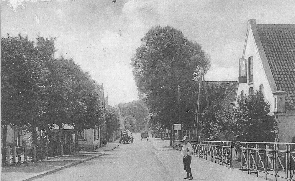 Die Burger Heerstraße von der Burger Brücke aus gesehen. Links die Einmündung zur Grambkermoorer Landstraße. rechts hinter dem Jungen das alte Geschäftshaus der Fleischerei E. Boes.