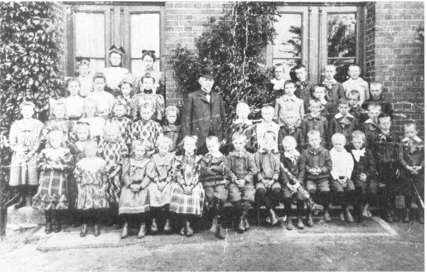 Eine Klasse vor der Mittelsbürener Schule mit ihrem Lehrer August Jacobs um 1910 .