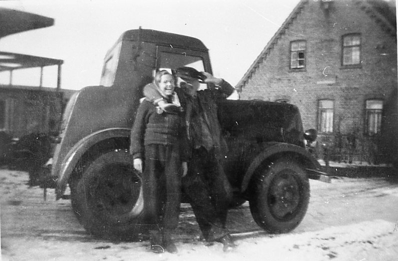 Müller Hinrichs vor Zugmaschine mit junger Frau, rechts das Haus