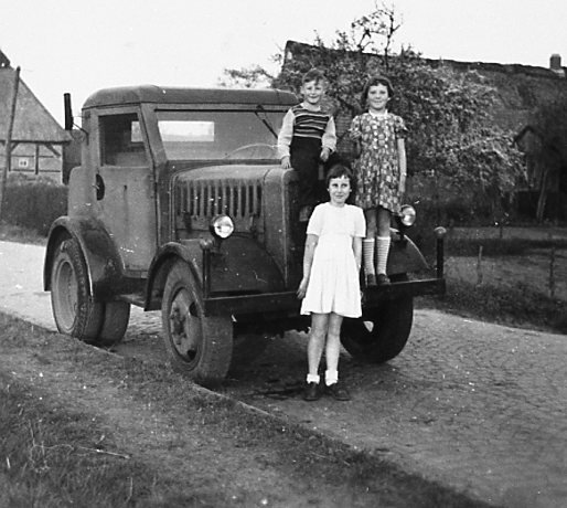 Helga Hinrichs vor der Zugmaschine, von Junge und Mädchen eingerahmt, die auf der Stoßstange stehen